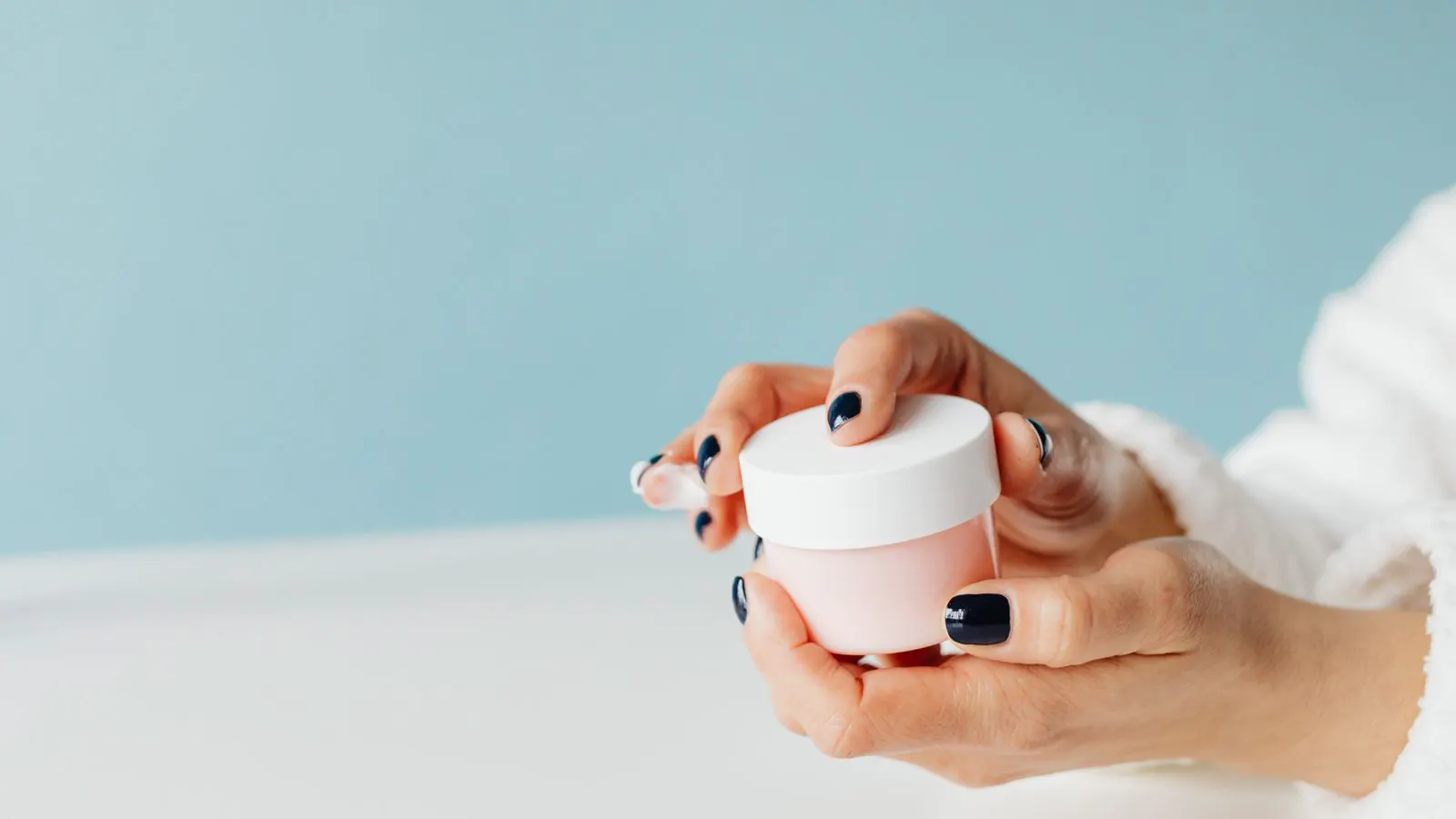 Close view of a skincare jar showing broken emulsion texture