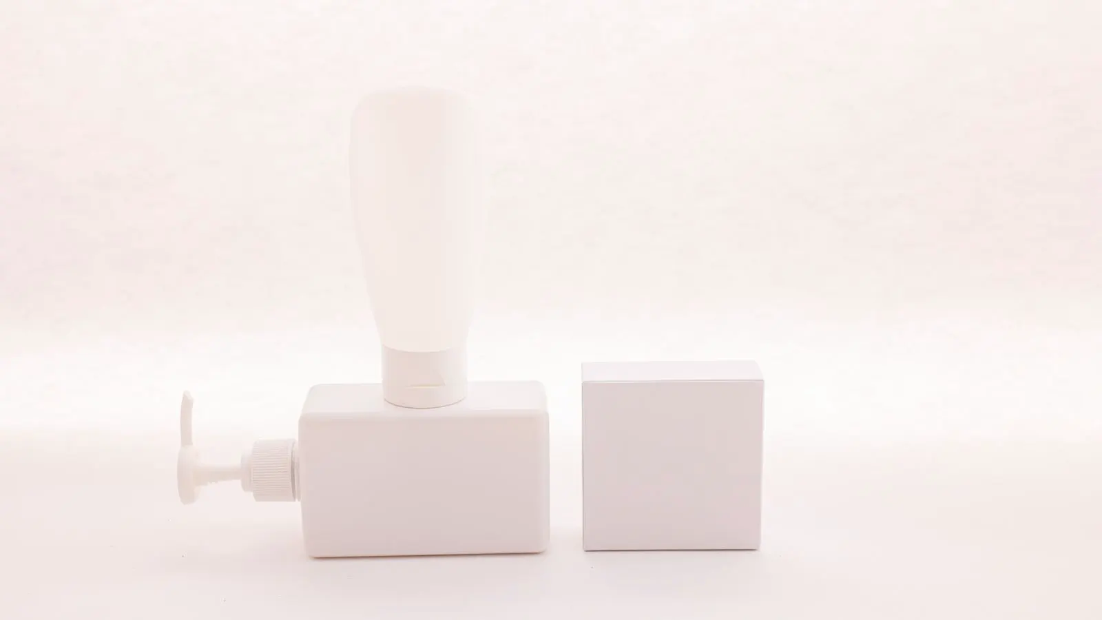 A clear glass cosmetic bottle with a black pump top on a white background.