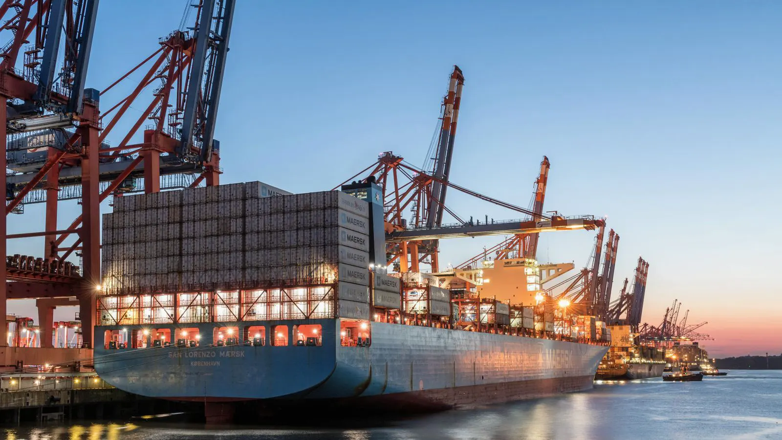 A large shipping container sitting on a dock near a crane.