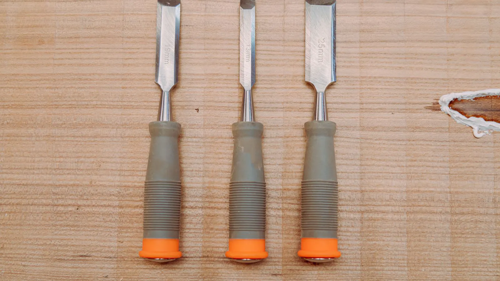 Heated rollers apply adhesive to a panel edge.