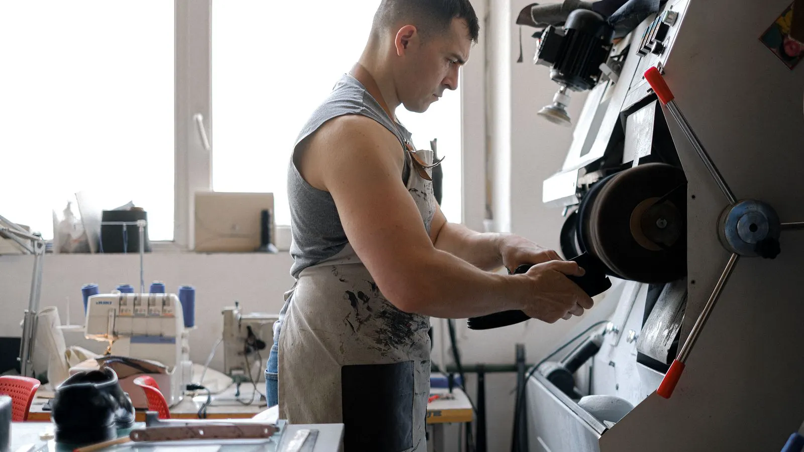 A professional operator adjusting a post-banding sanding machine in a factory.