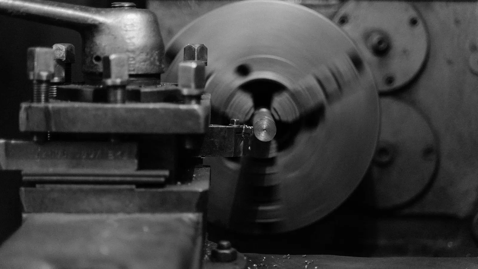 Workers inspecting a precision machined metal part on a factory floor.