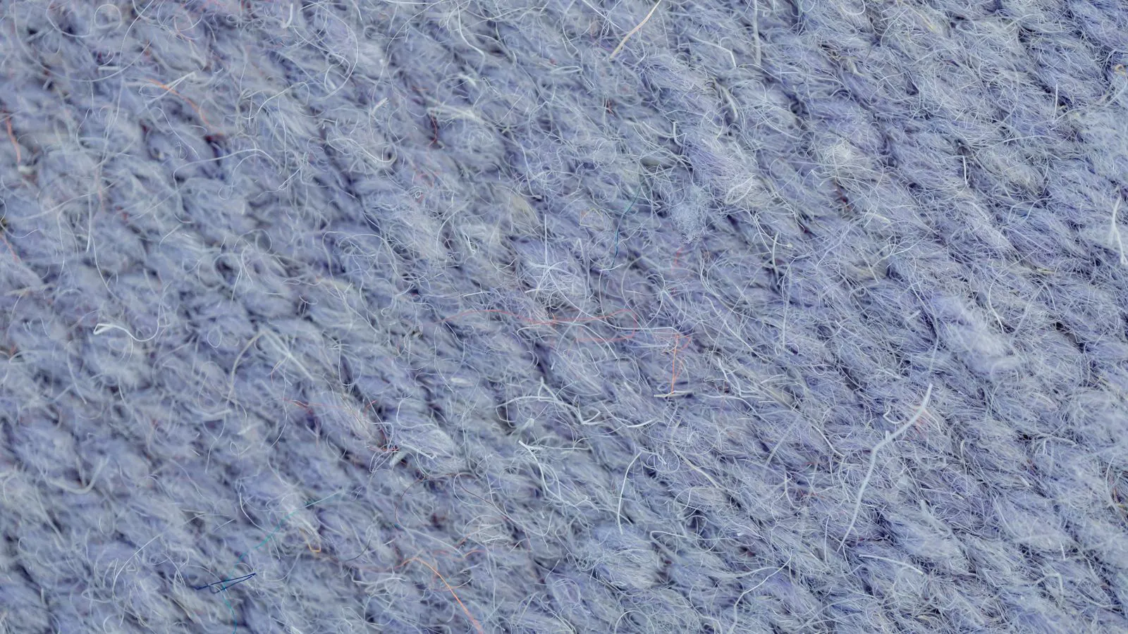 Close-up view of a knitting machine producing a sample knit fabric.