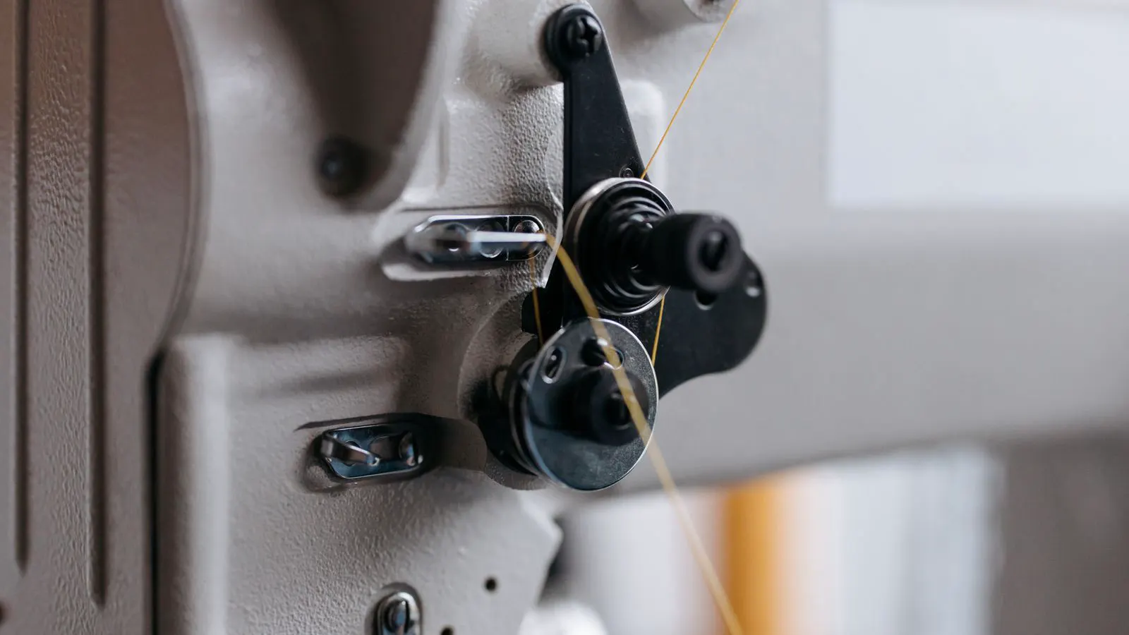 Technician inspecting a sewing machine in a clean factory environment
