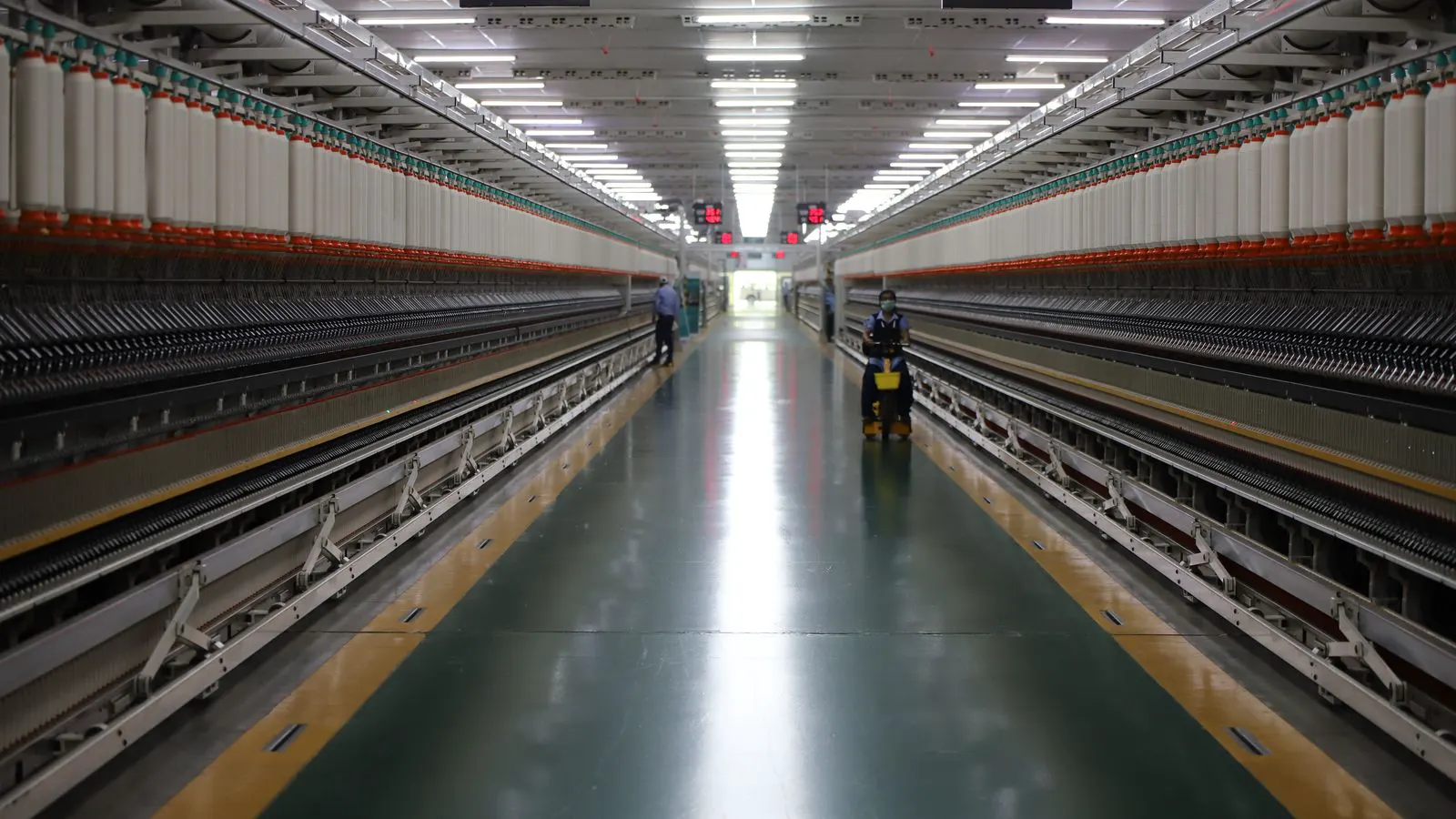 A large industrial dyeing machine on a factory floor with control panels.