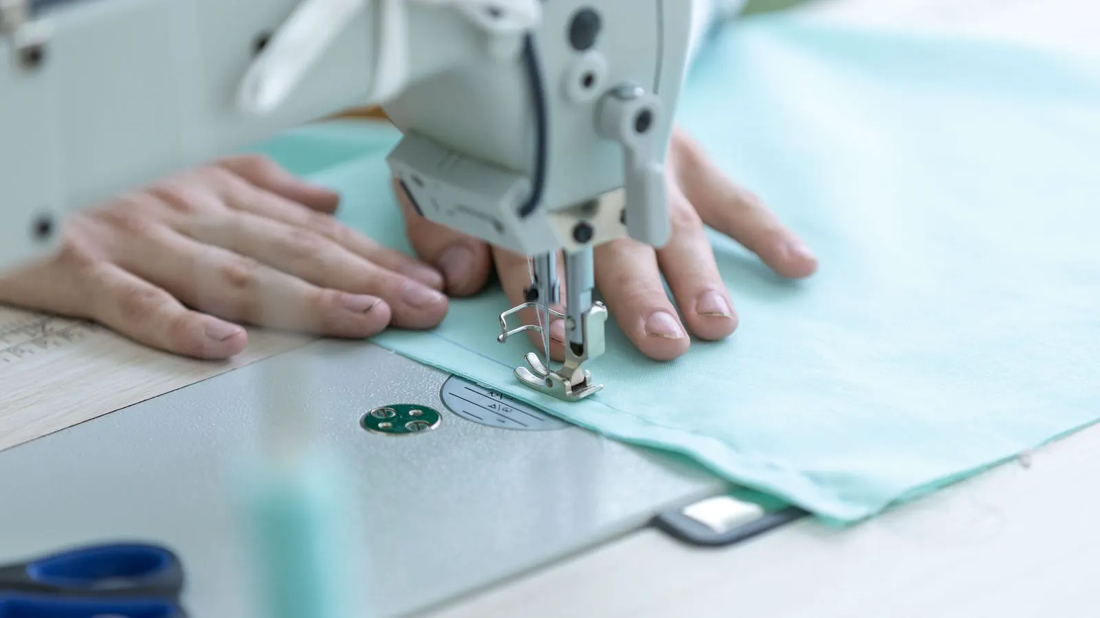 A flatbed sewing machine processing a piece of black stretch knit fabric.