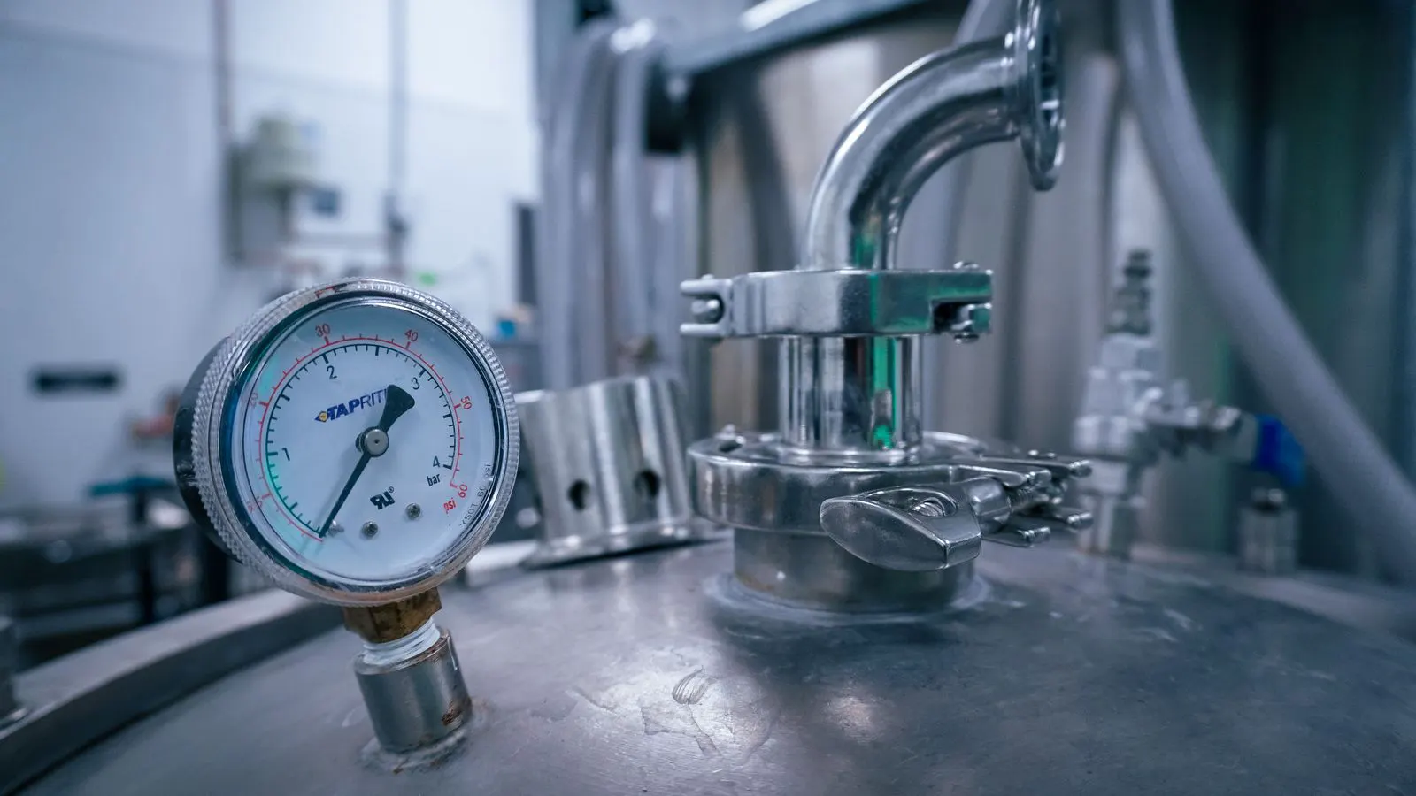 Stainless steel tank connected to industrial dyeing machine pipes