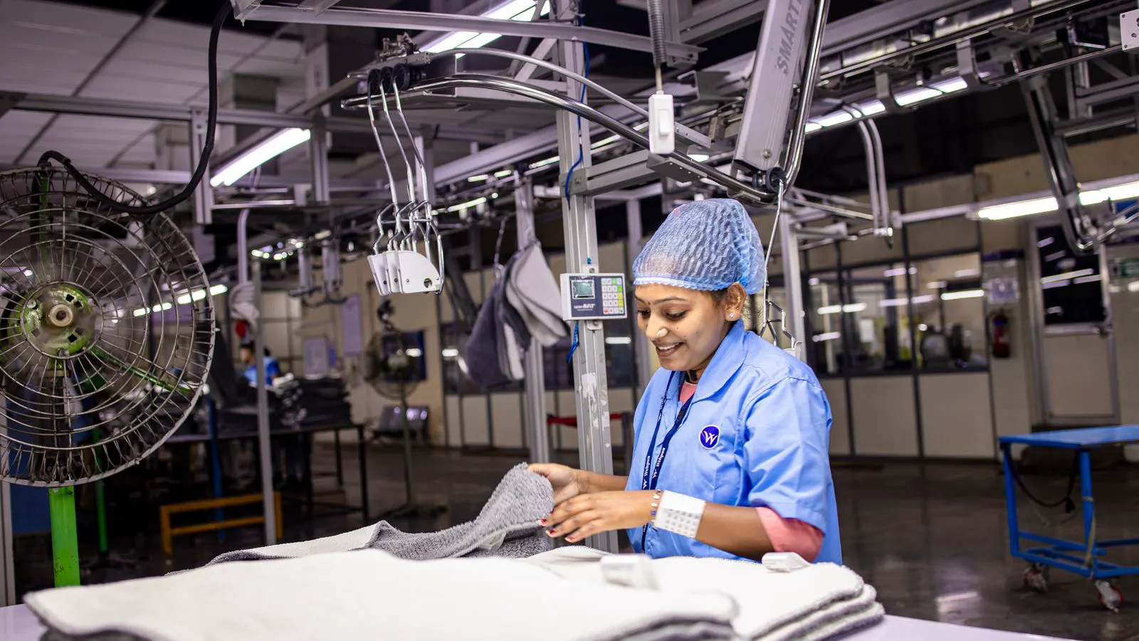 A textile machine engineer reviewing printed financial reports at a workbench.