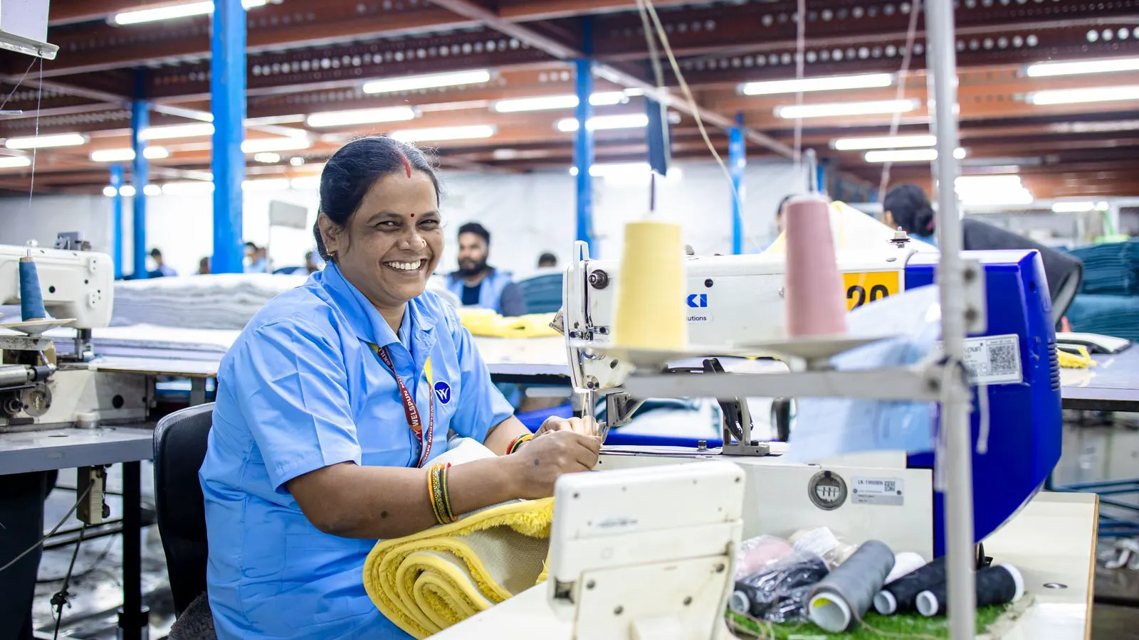A modern industrial sewing machine running in a clean factory floor.