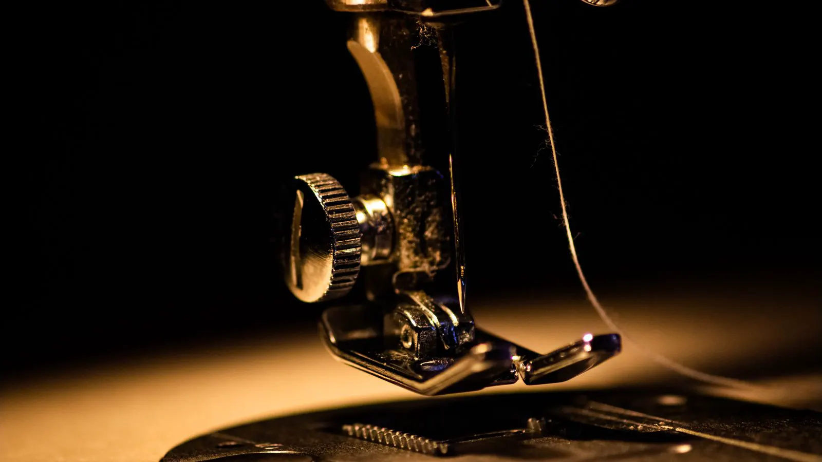A close up view of an industrial sewing machine needle bar and hook