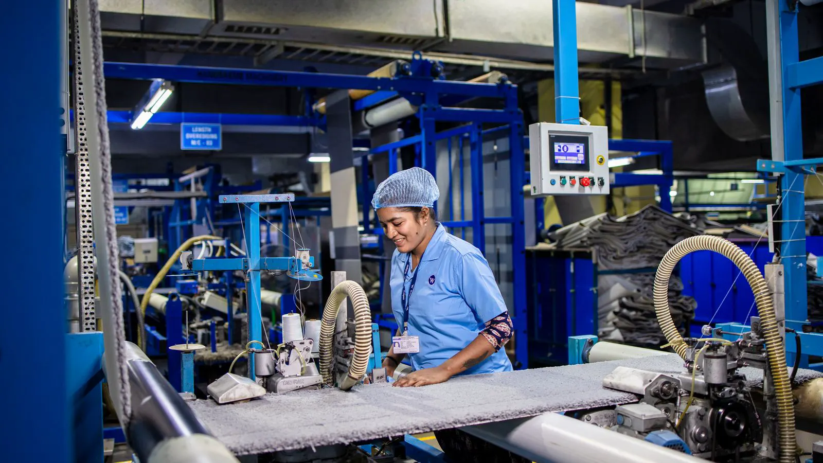 Technician inspects the needle bed and carriage of a production machine.