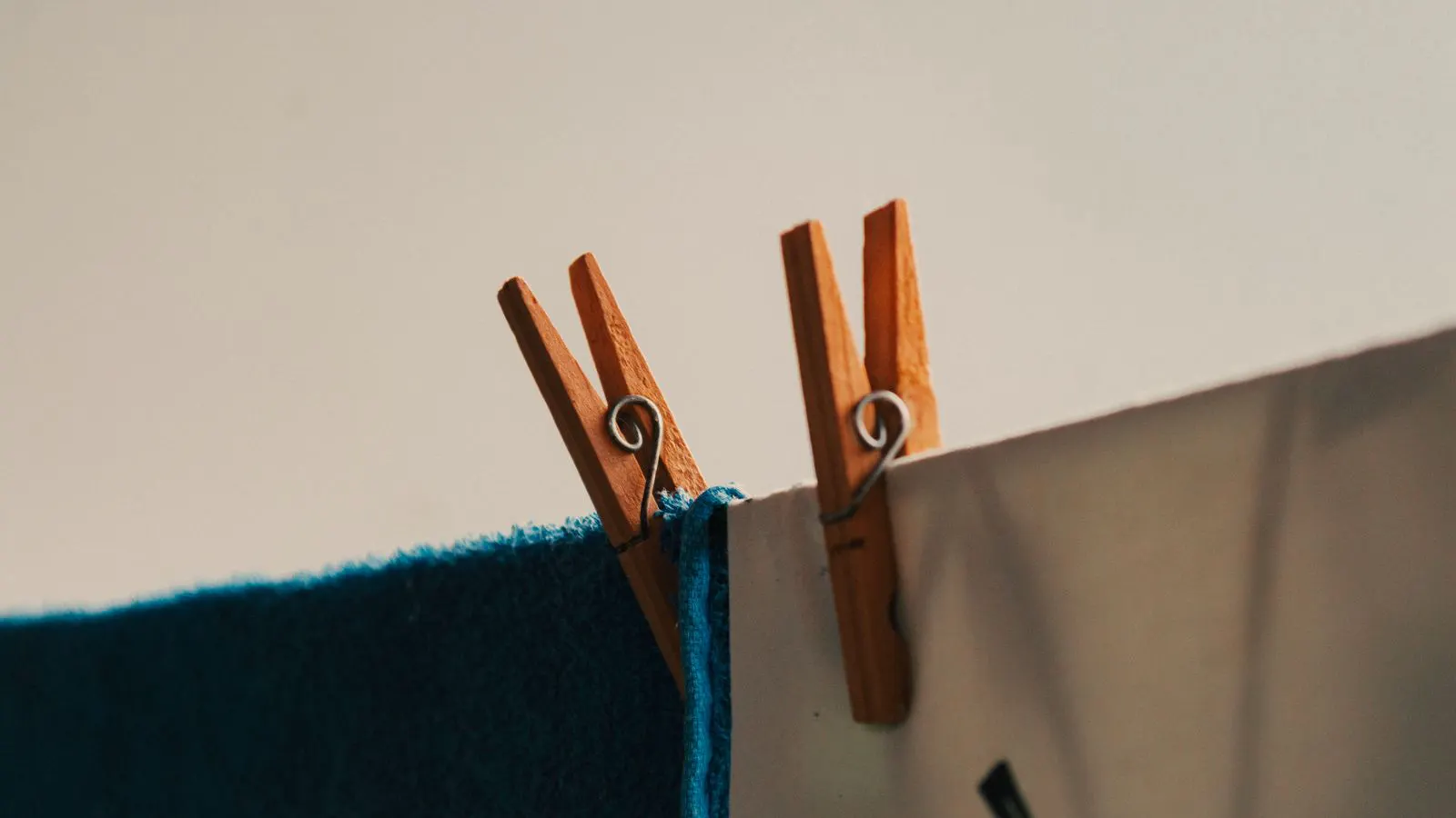 A robotic arm gripper holding a small piece of light colored fabric