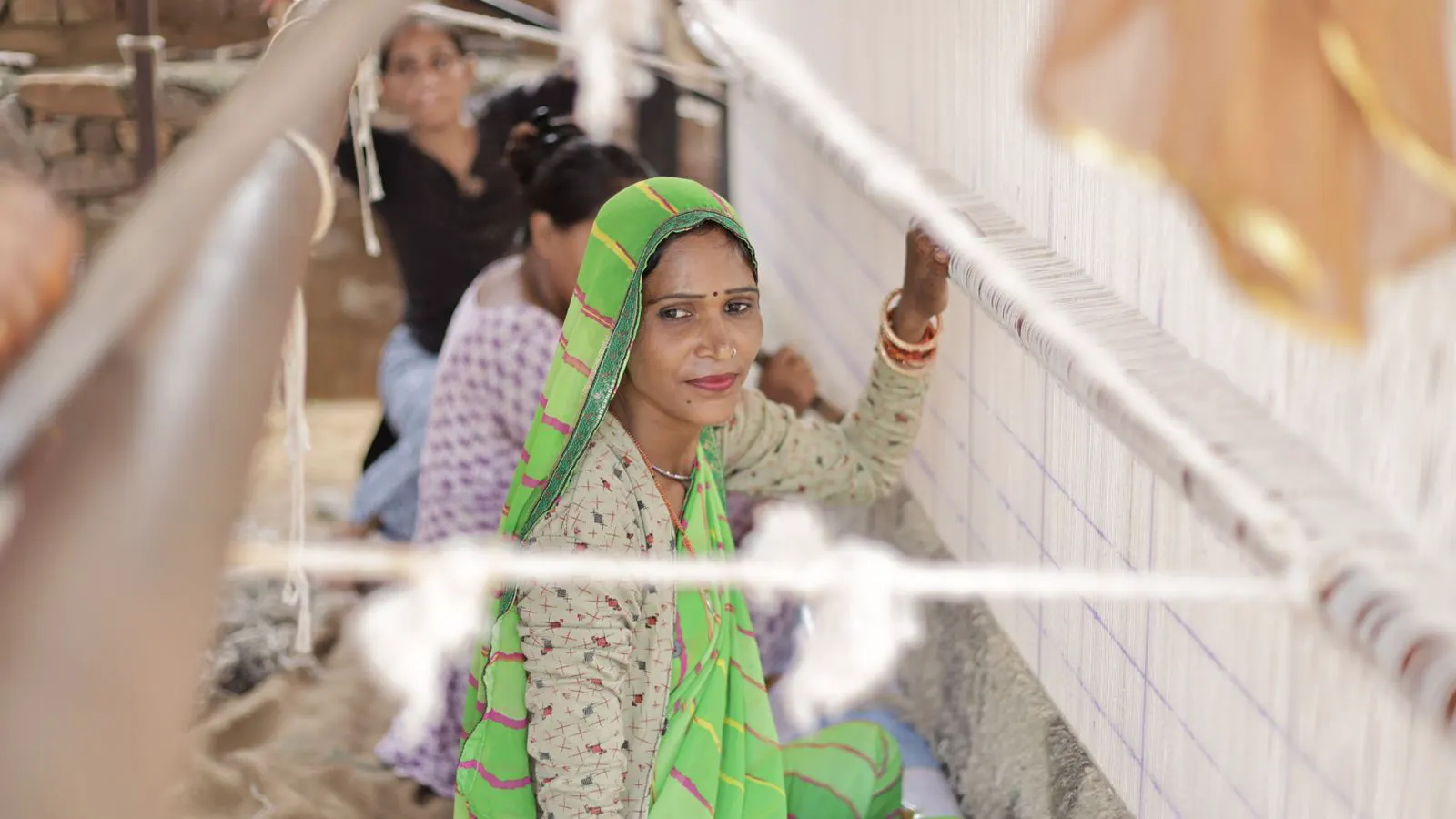 A worker adjusting warp tension on a modern weaving machine