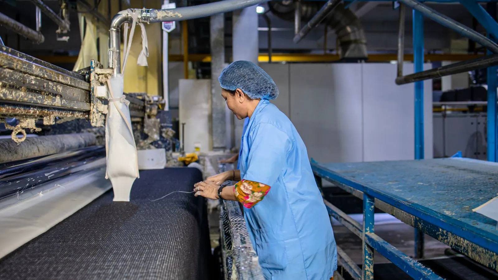 A modern power loom with heddles and warp threads in a textile mill