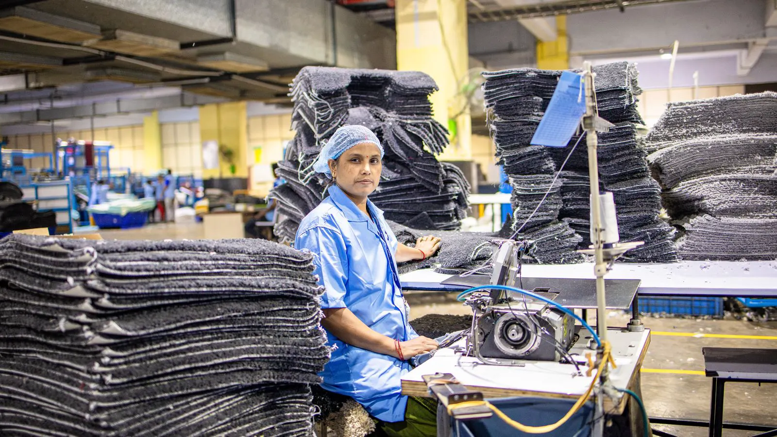 A worker operating an industrial sewing machine in a factory