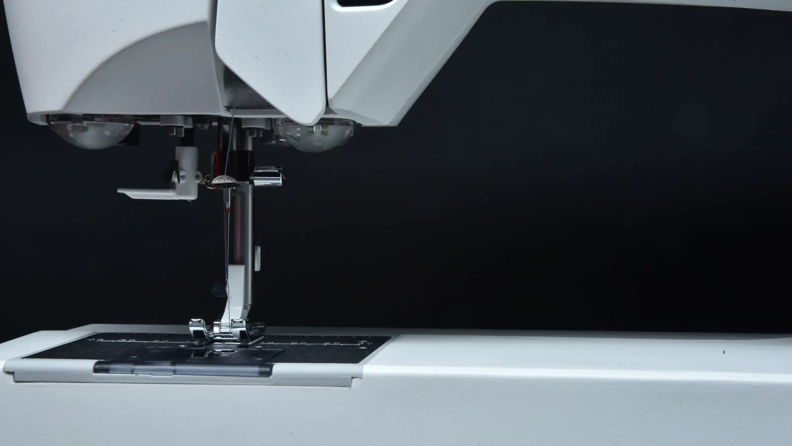 A technician holding a new industrial needle next to a sewing machine