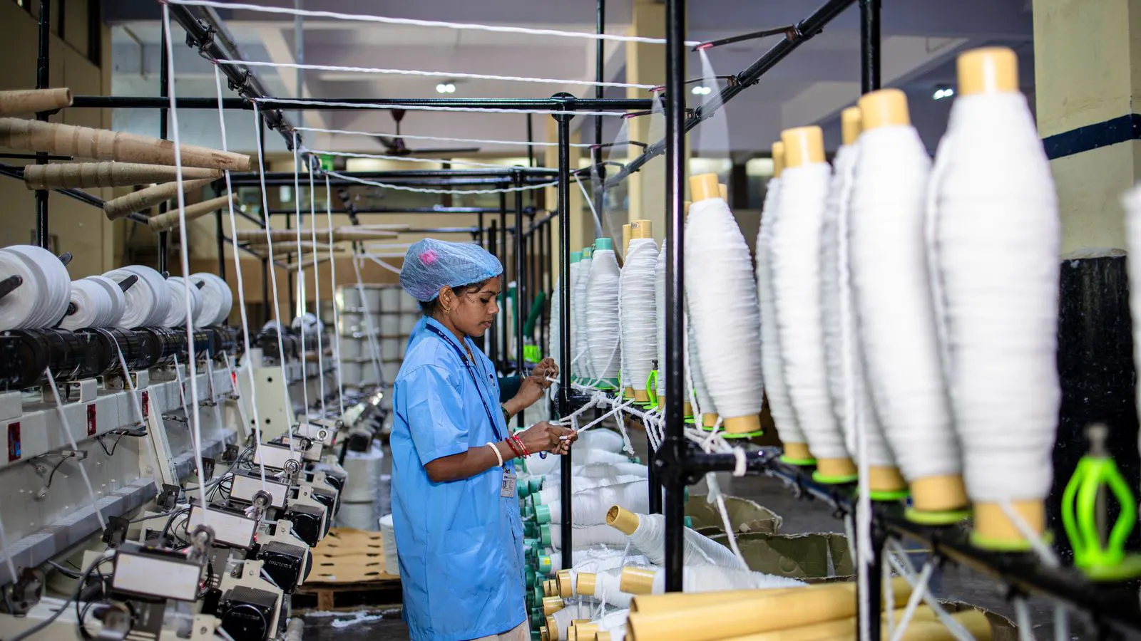Close view of yarn spools on a spinning frame with visible tension