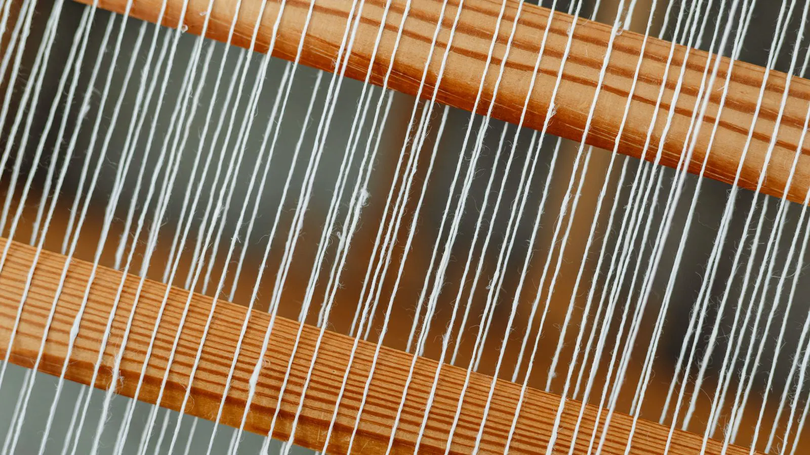 A close-up view of a weaving loom with warp threads.