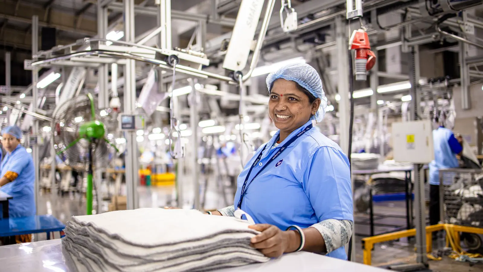 A modern textile factory floor with automated machinery and digital control panels.