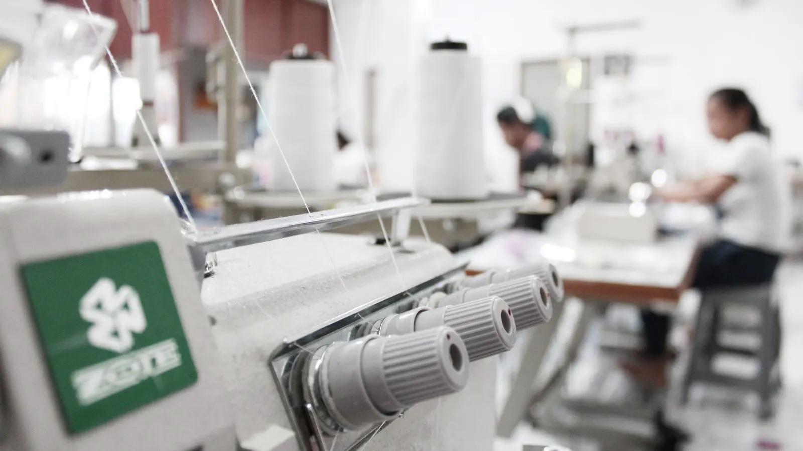 Technician adjusting tension guides on a circular knitting machine