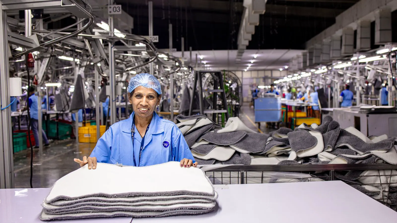 A modern textile machine sits on a factory floor with an asset tag.
