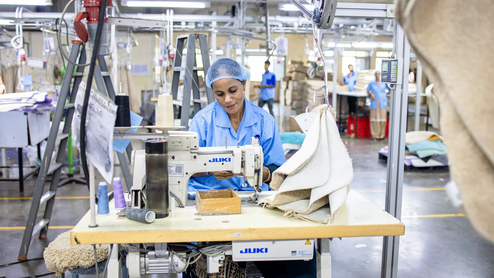 operator feeding layered heavy fabric through industrial sewing machine