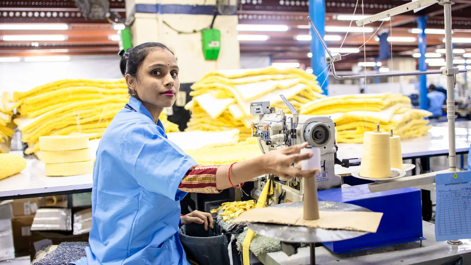 A technician checks the power meter on a spinning frame.