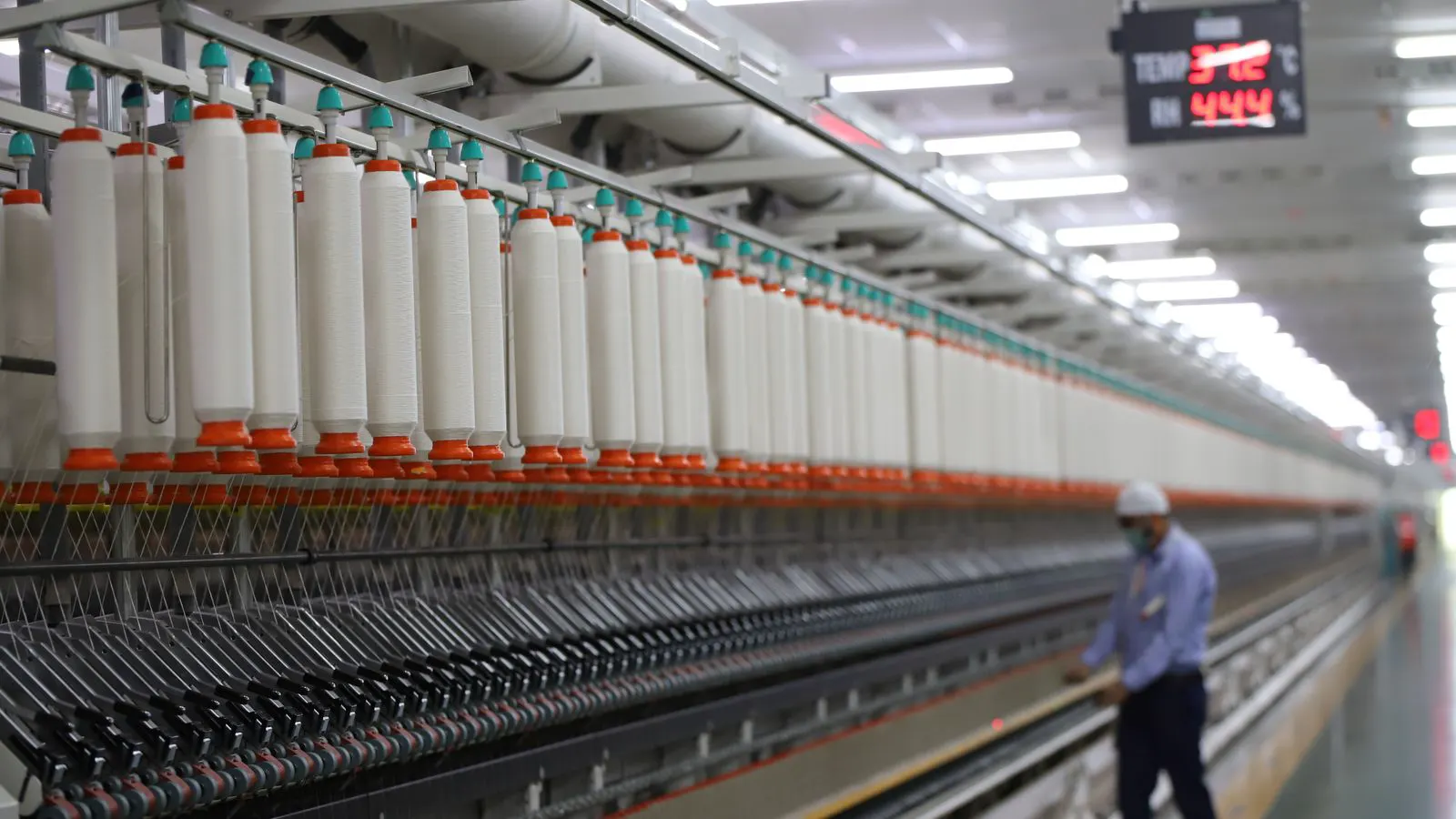 Rows of spinning bobbins and machine components in a textile facility