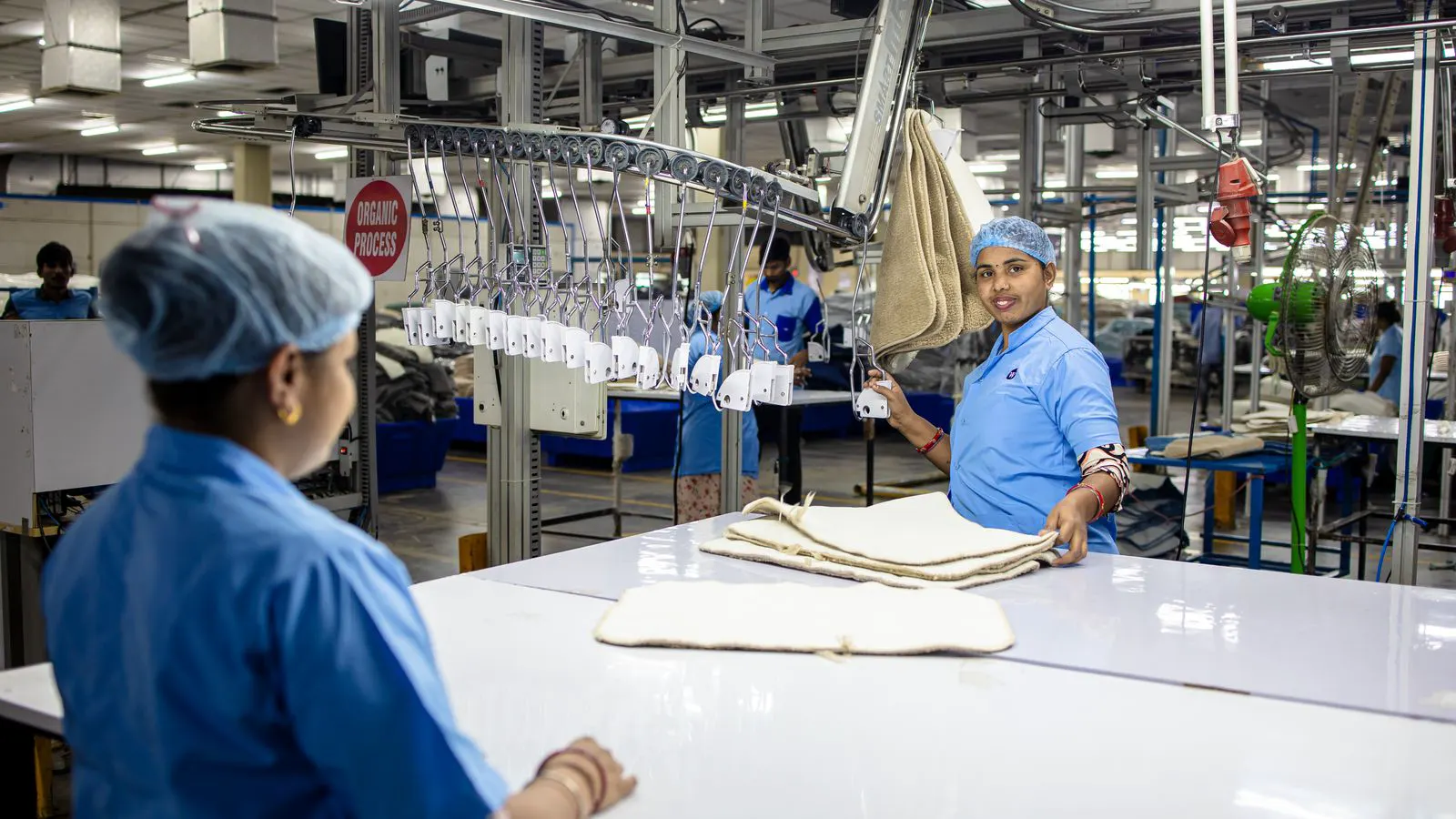 A collaborative robot arm positioned near a fabric handling station in a textile plant.