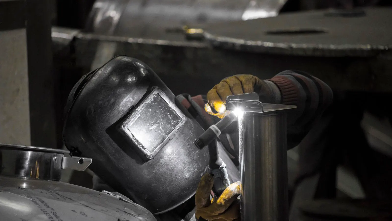 A worker using a gauge to inspect a welded metal joint