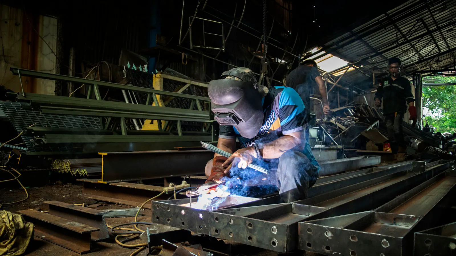 A worker measures a sheet metal panel with a caliper.
