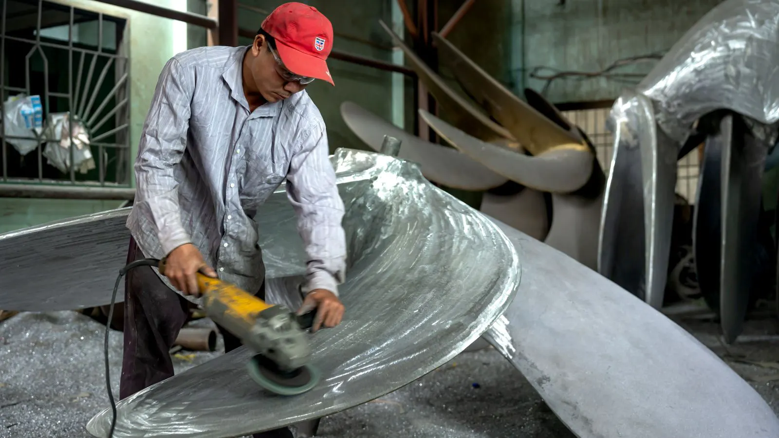 A worker inspecting a bent sheet metal part on a bench