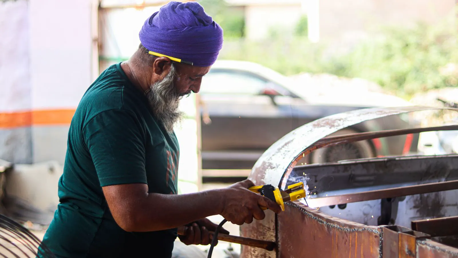 TIG welder working on a stainless steel sheet in a shop