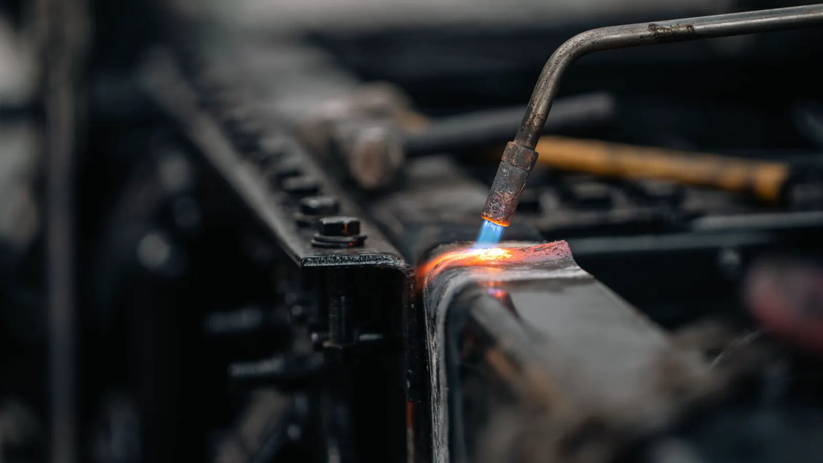 A worker performing manual welding on a flat sheet metal panel.