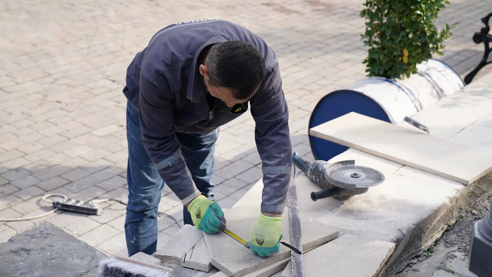 A technician measures a flat metal panel with a digital caliper.