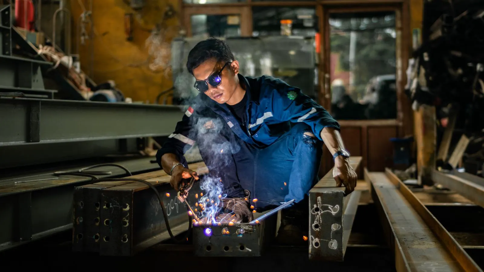 A welder examining a finished weld joint on stainless steel
