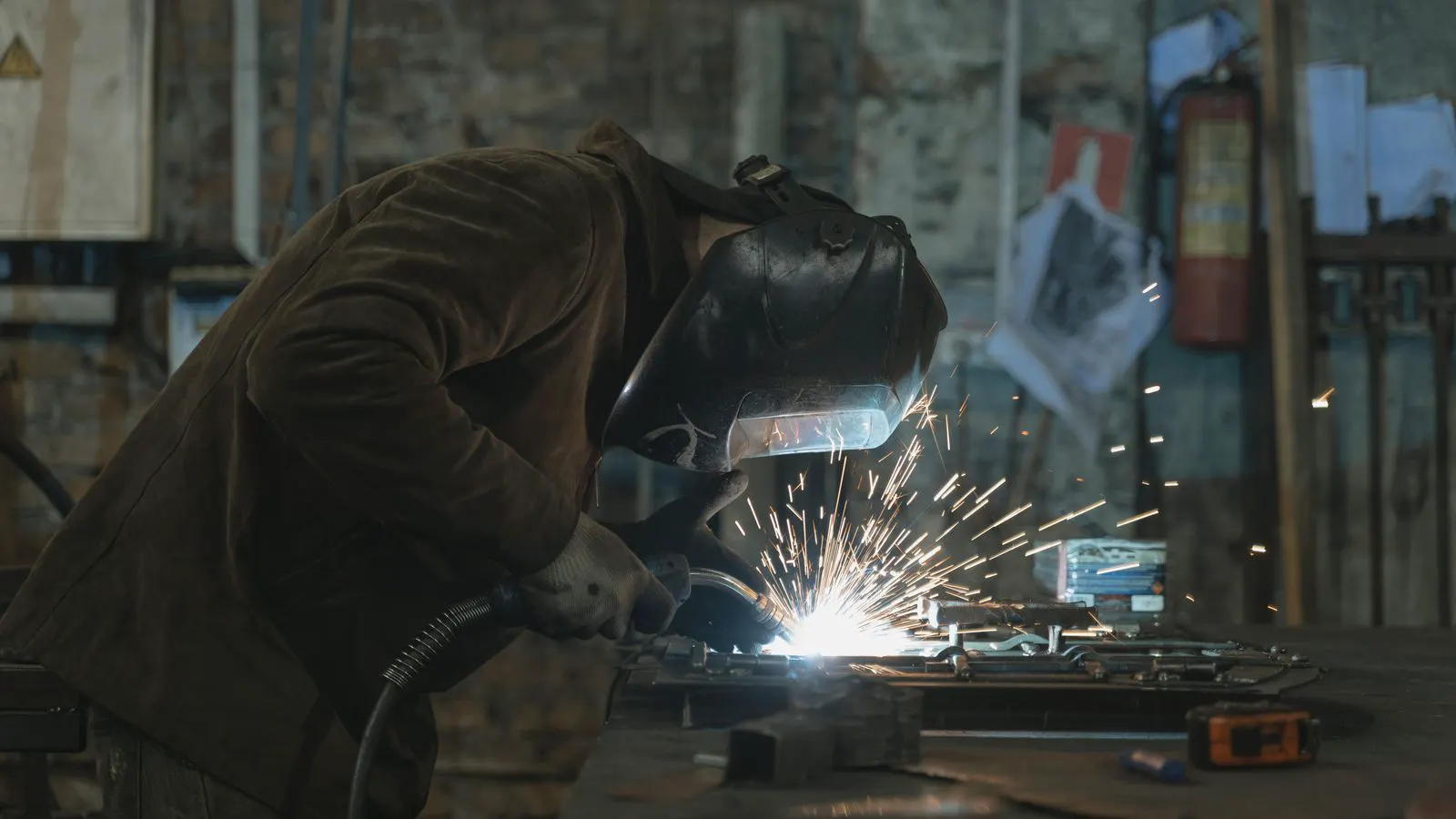 A technician grinding a cracked weld seam on a flat metal panel.
