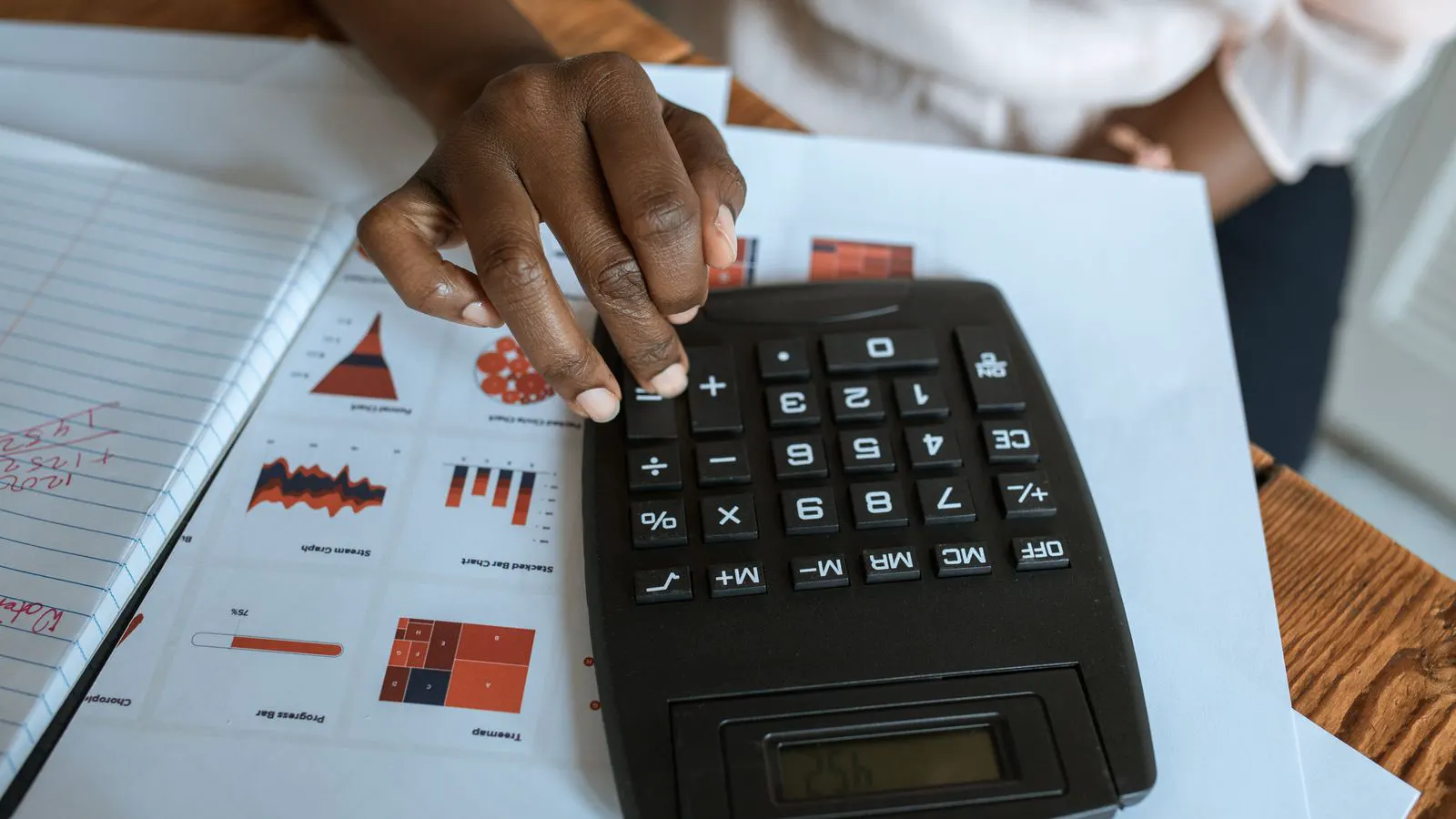 A desk with printed financial statements and a calculator next to a contract