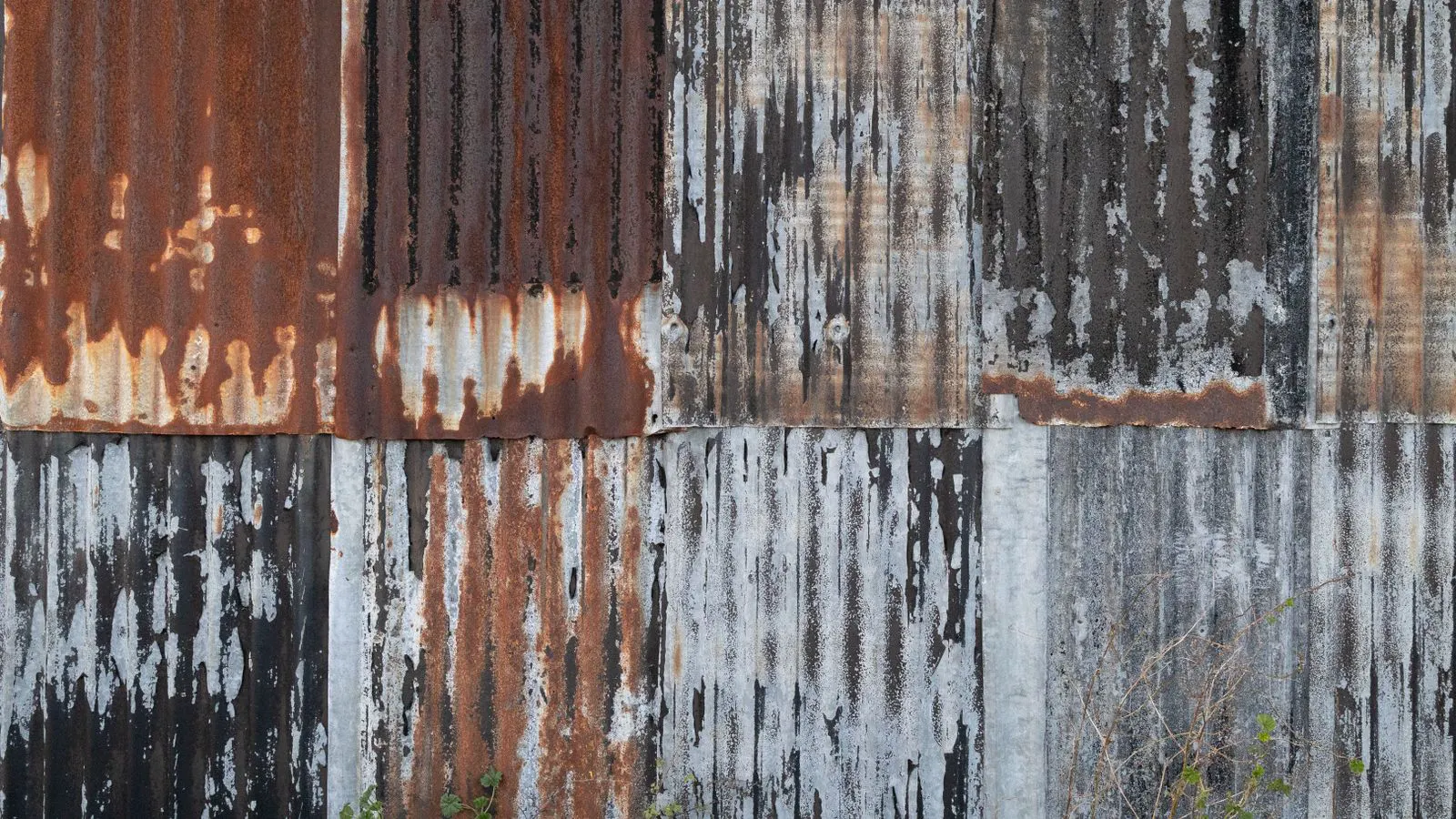 A close-up of a steel panel with a flaking surface coating