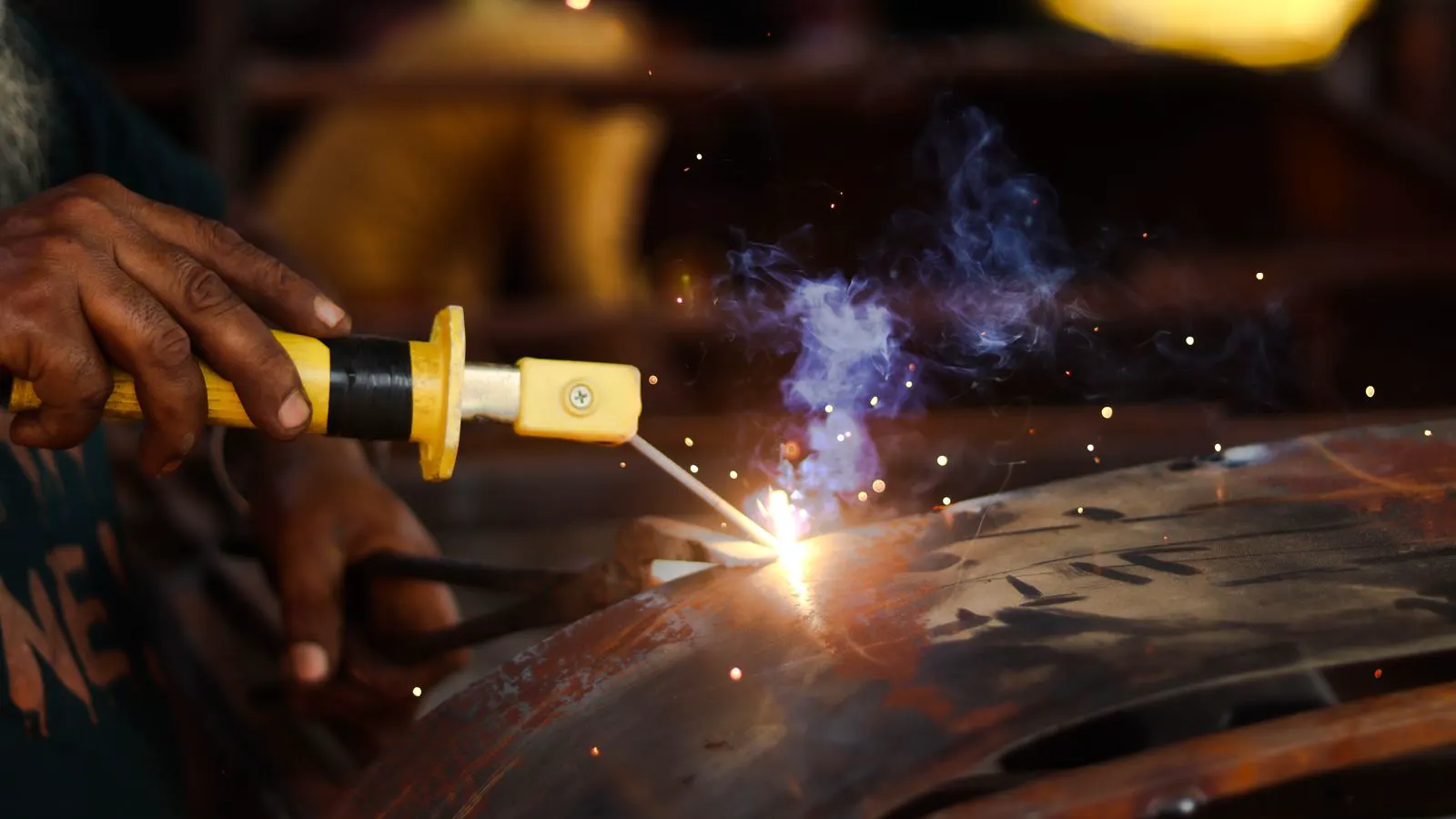 A technician examining the seam of a welded sheet metal panel with a lamp.