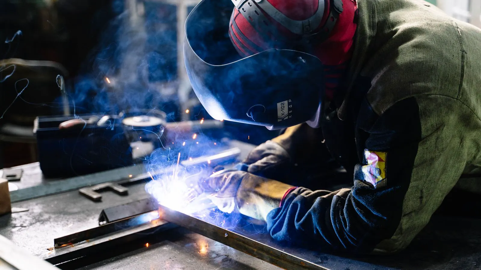 A metal worker assembling a fabricated sheet metal panel in a workshop.