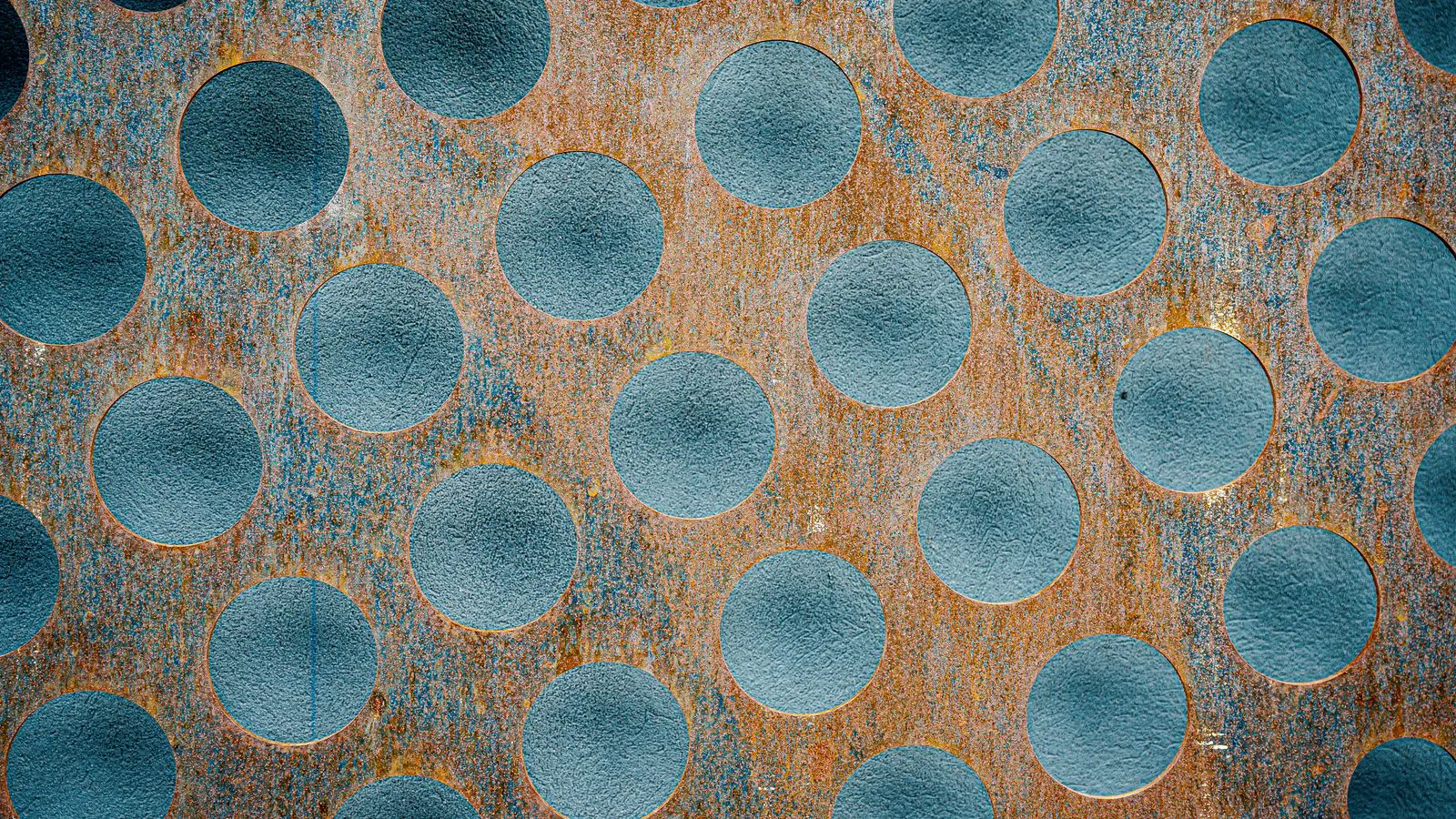 A roll of metal sheet material sits on a rack in a workshop.