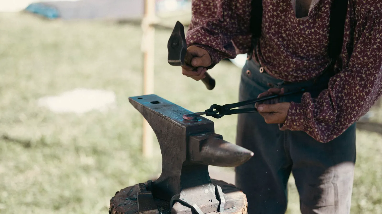 Metal forging hammer striking a workpiece on an anvil in a plant.