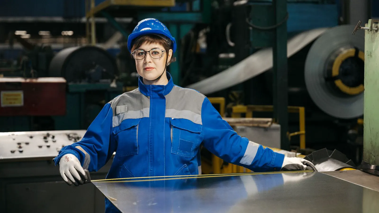 A worker inspecting a hot forged metal component in a factory
