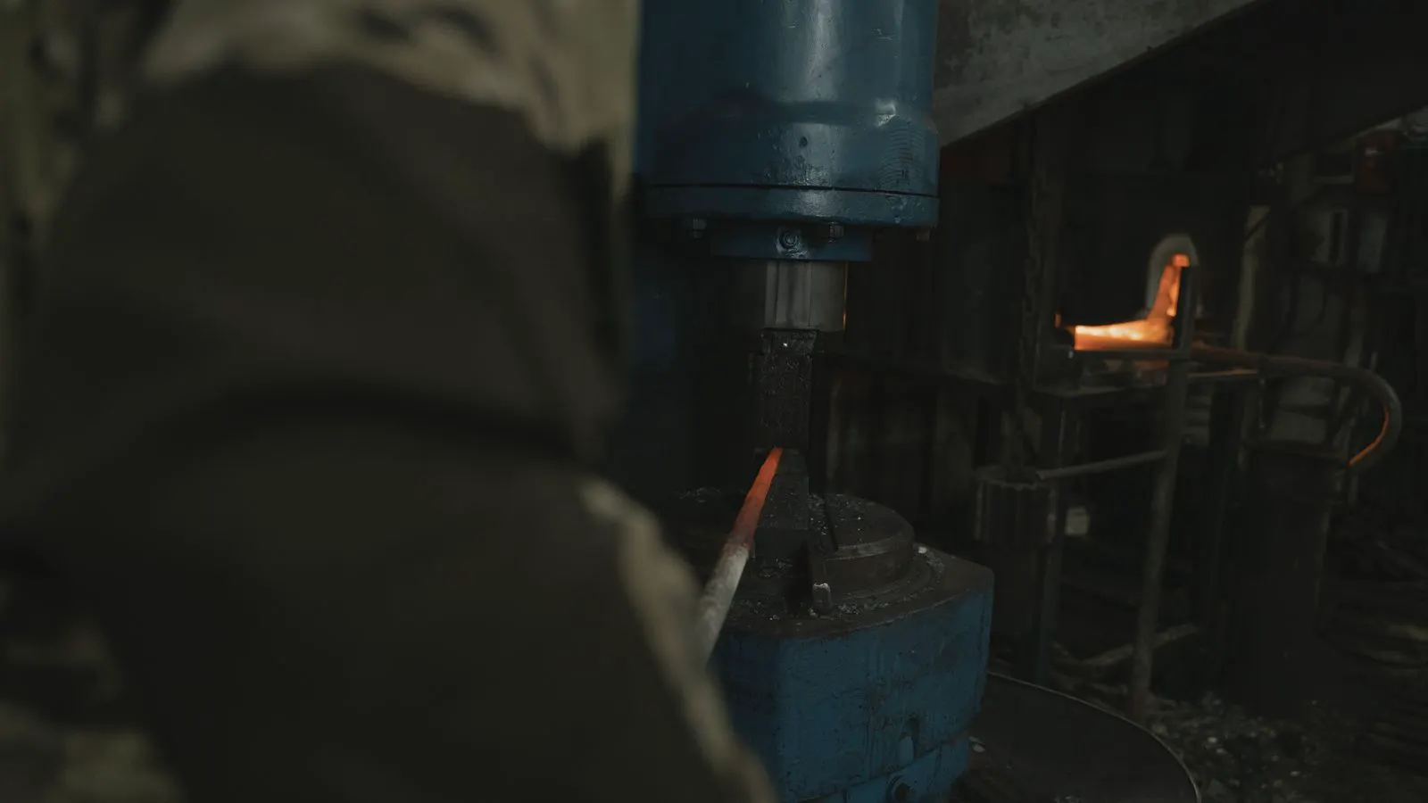 Workers inspecting newly forged steel components on a production floor.