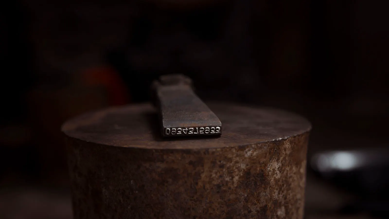 Induction hardening coil positioned over a forged metal component in a workshop