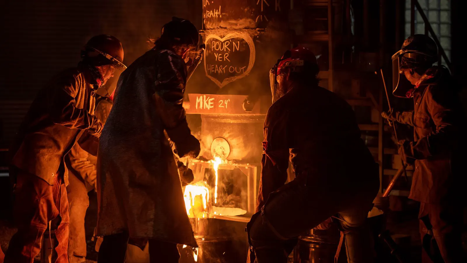 A worker in protective gear near a large industrial furnace